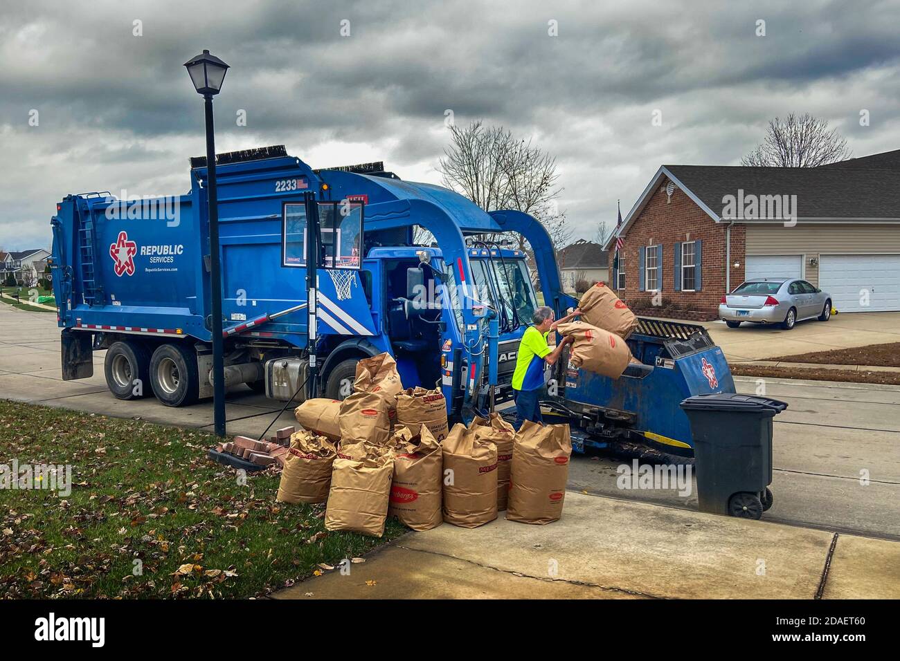 Shiloh, il - 10 novembre 2020; Republic Services camion trasportatore di rifiuti e conducente che raccoglie rifiuti di cantiere compostabili in sacchi di prato e foglia in area residenziale Foto Stock