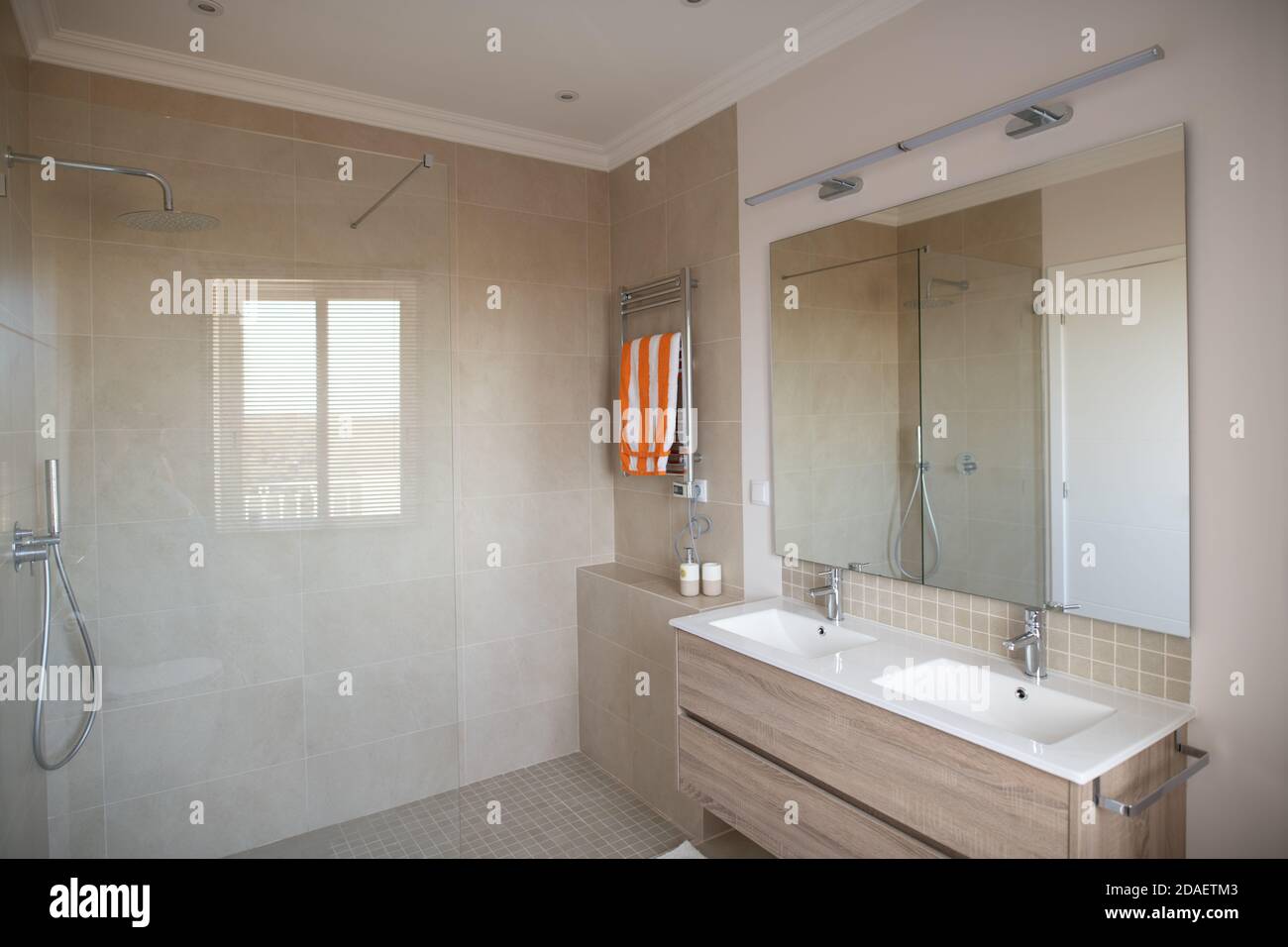 Bagno interno con grande doccia piastrellata e doppio lavabo con specchio Foto Stock