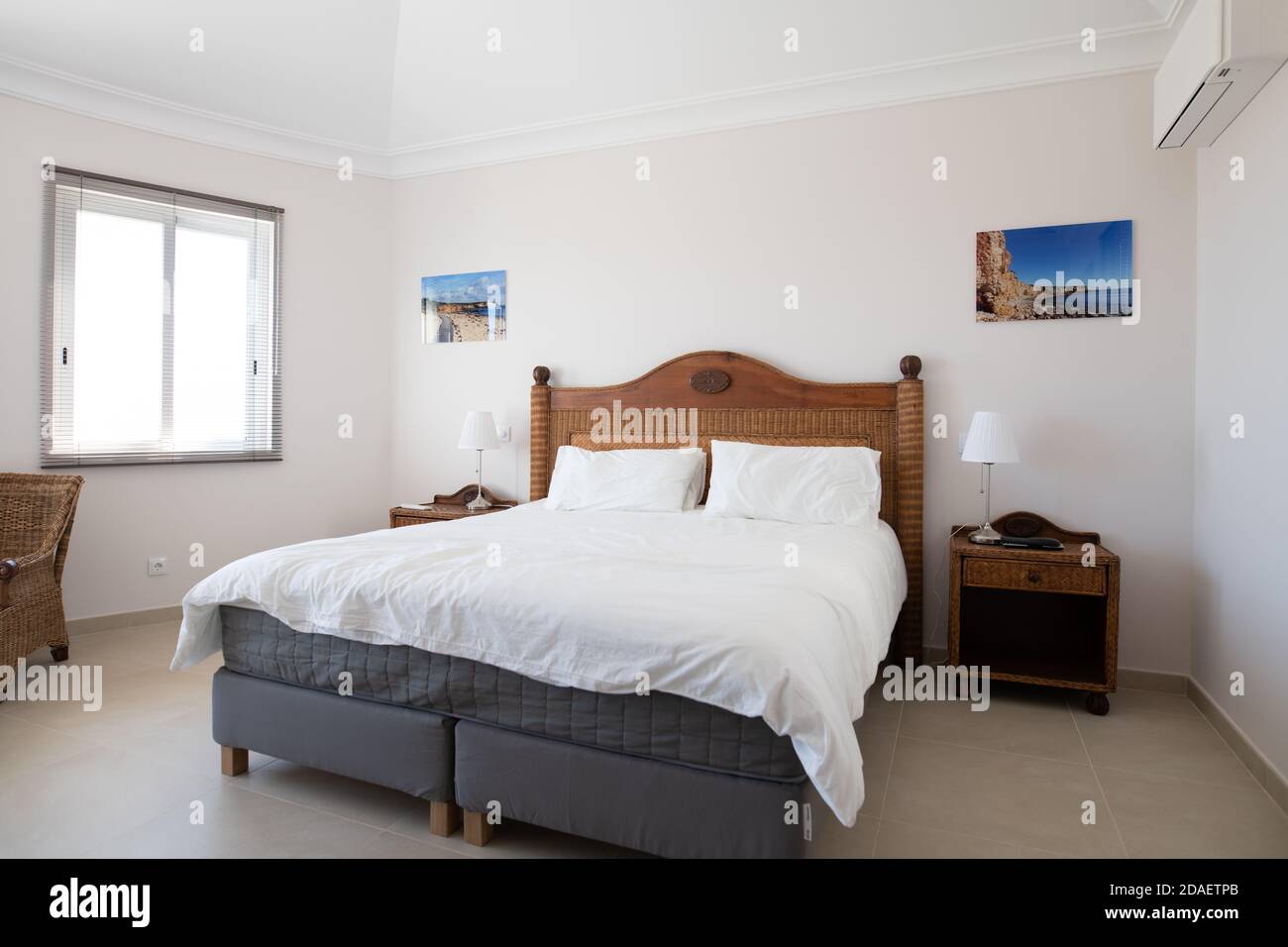 Camera da letto principale con mobili in legno e biancheria da letto bianca in una villa per vacanze ristrutturata Foto Stock