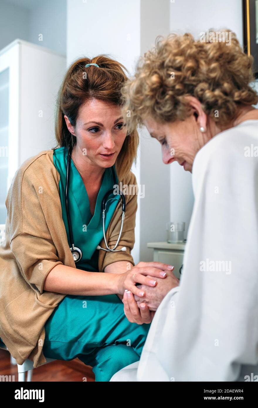 Medico dando incoraggiamento al paziente anziano Foto Stock