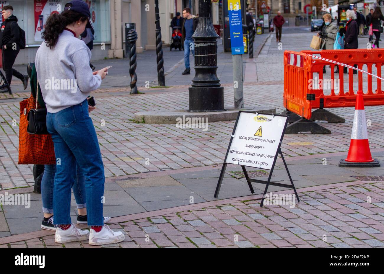Dundee, Tayside, Scozia, Regno Unito. 12 Nov 2020. Notizie del Regno Unito Covid-19 Lockdown. A Dundee c'è stata una quantità minore di persone in giro per le strade e alcuni negozi essenziali aperti dal momento che è stata applicata la restrizione più severa di Lockdown di livello 3 Covid-19. Alcuni residenti locali sono ben consapevoli delle linee guida per le distanze sociali e l'uso di maschere facciali sono fuori shopping nel centro della città in un freddo pomeriggio di novembre. Credit: Dundee Photographics/Alamy Live News Foto Stock