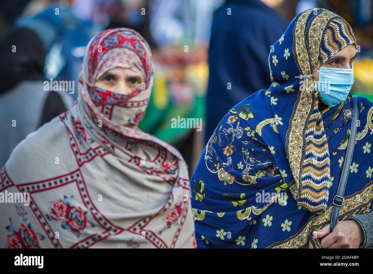 Londra, UK - 3 Novembre, 2020 - le donne musulmane asiatiche che indossano una maschera facciale (messa a fuoco sulla destra) e un hijab come copertura del viso mentre fanno shopping a Walthamstow m. Foto Stock