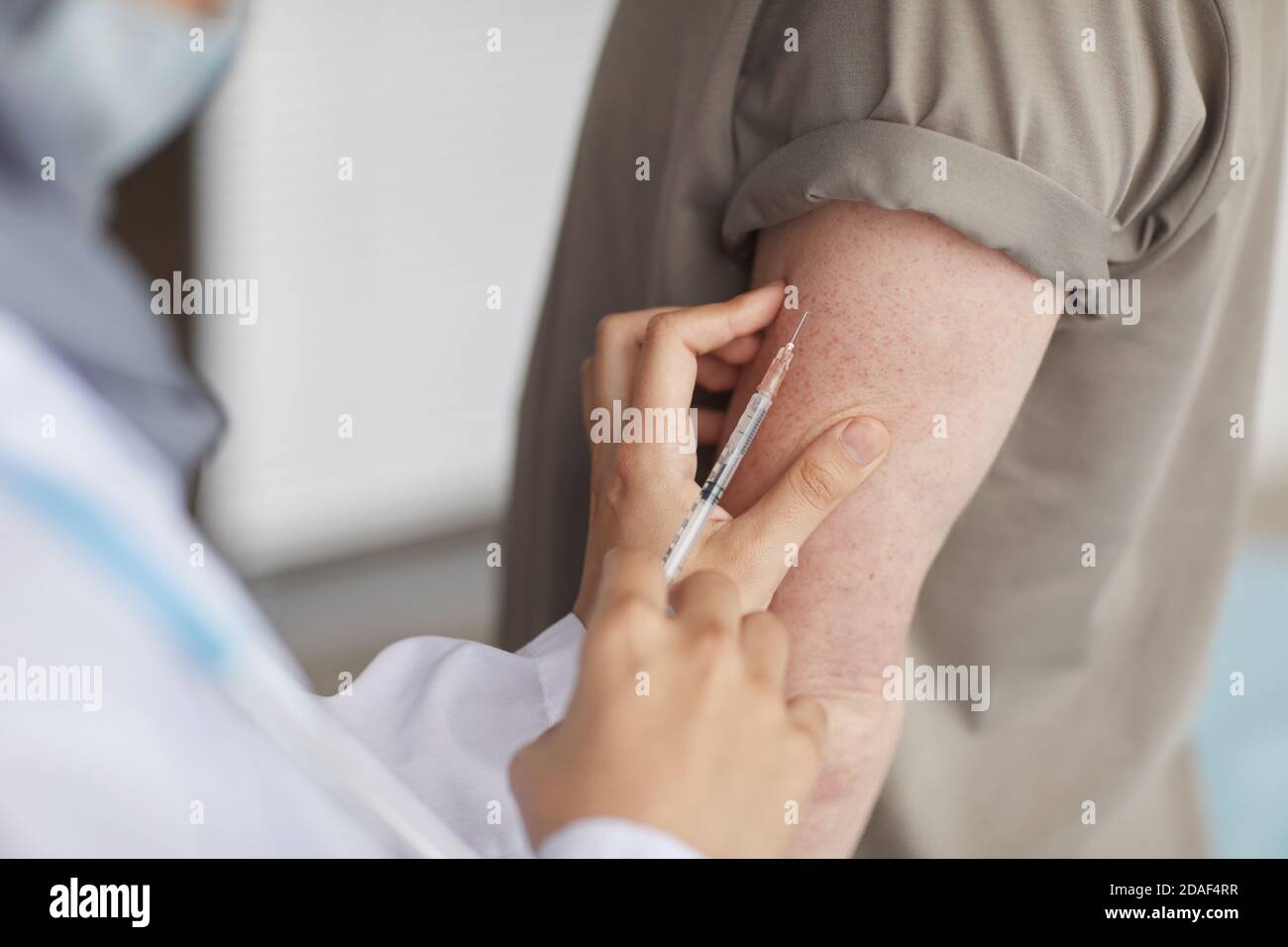 Primo piano del medico che dà un'iniezione al paziente nel suo mano Foto Stock