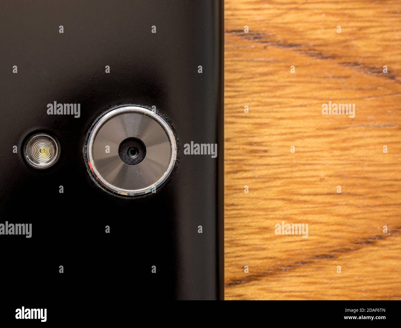 Primo piano di una fotocamera per smartphone con flash luminoso. Sul lato destro della foto sfondo vuoto con sfondo in legno. Foto Stock