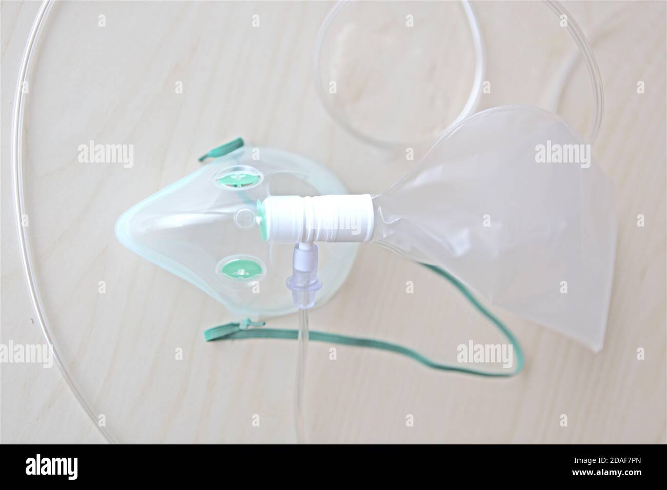 Maschera di ossigeno isolata per la cura della covid apparecchiature mediche per la respirazione supporto all'ospedale su tavolo di legno Foto Stock