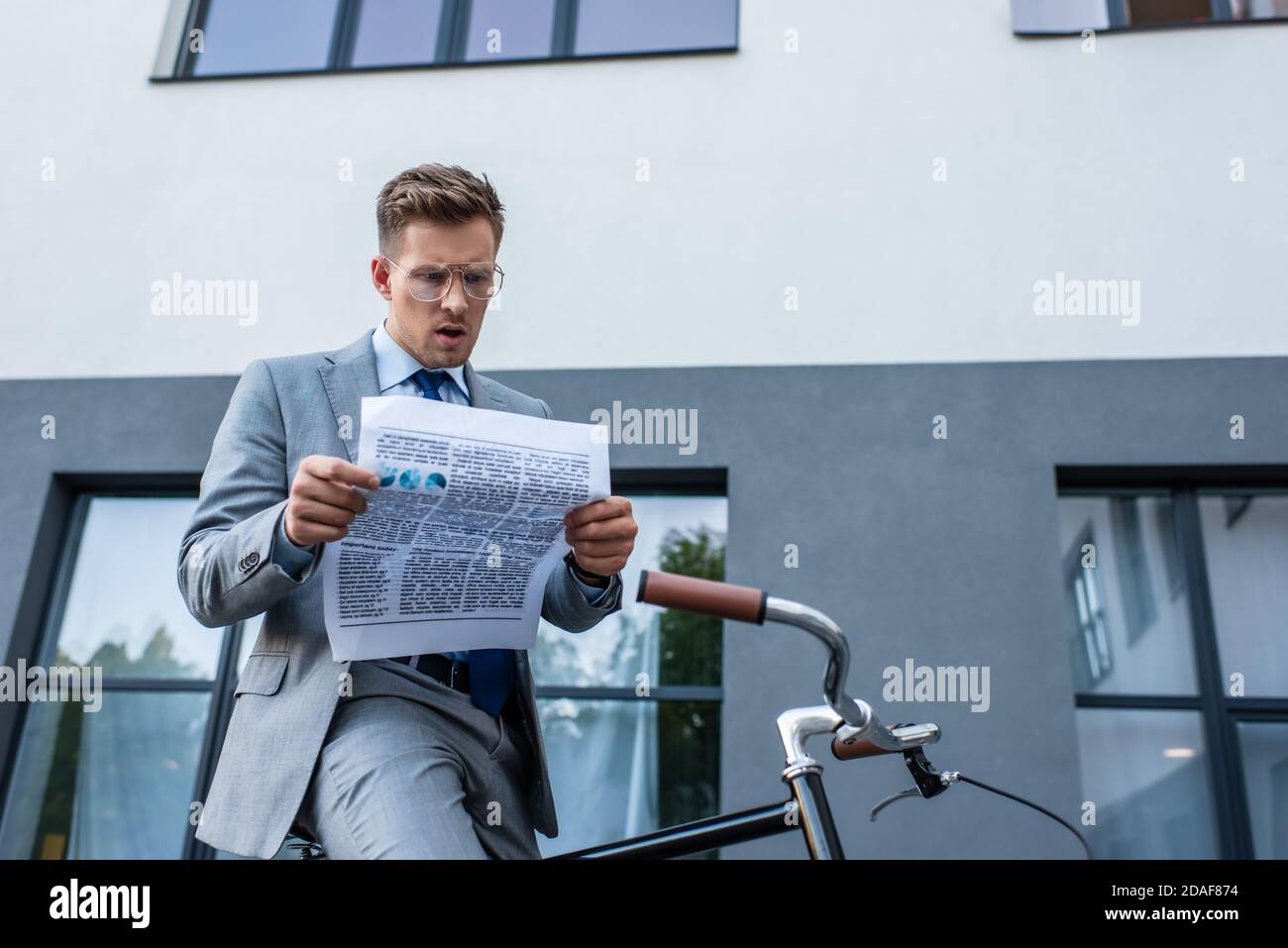 Concentrato uomo d'affari lettura giornale vicino bici all'aperto Foto Stock