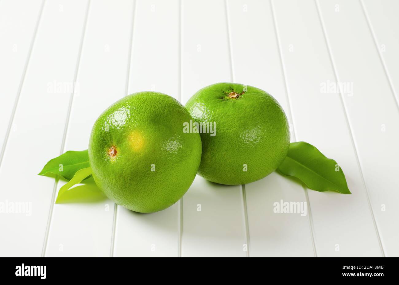Due frutti interi di amissina (pompelmo verde, pomeliti) e foglie Foto Stock