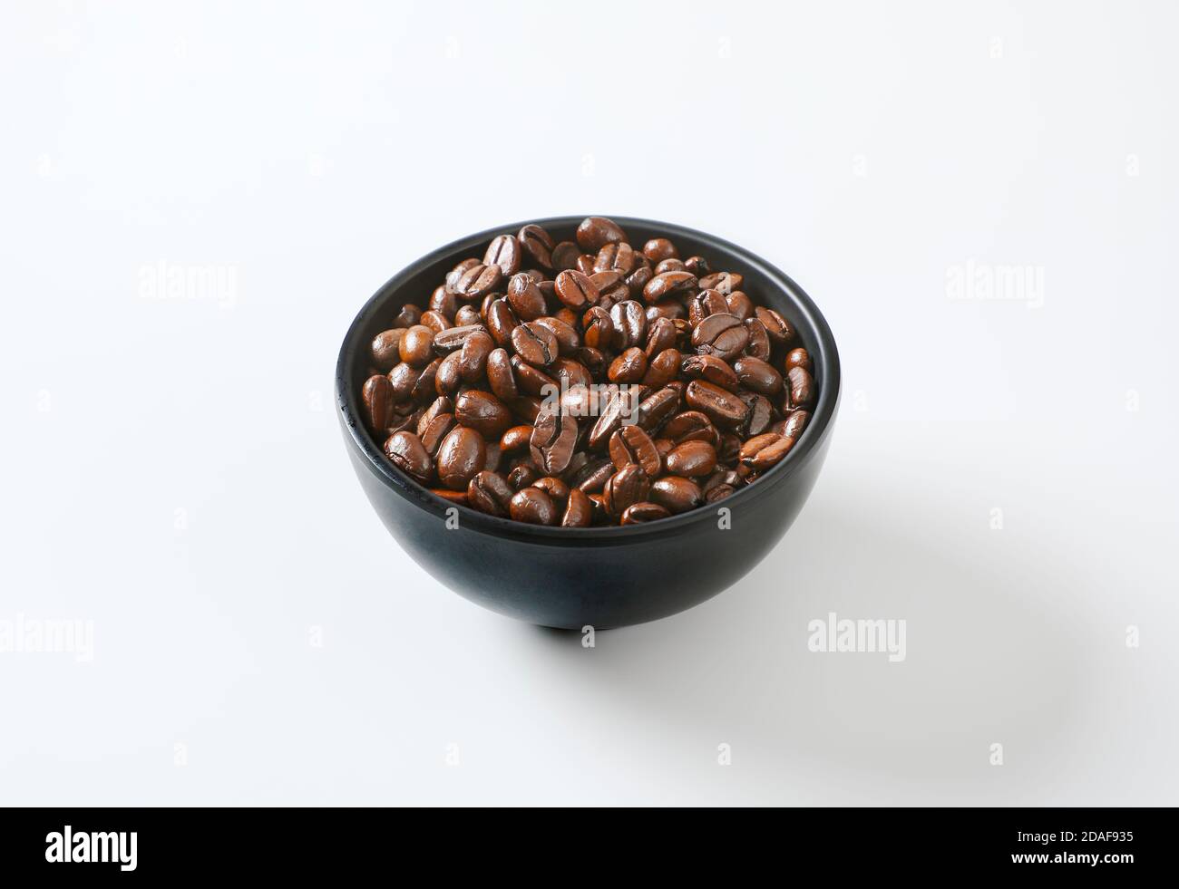Chicchi di caffè tostati in ciotola nera Foto Stock