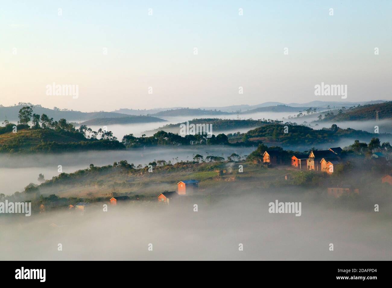 Paesaggio di case di villaggio con foresta pluviale tropicale in montagna in mattina nebbia, vicino Perinet, Madagascar Foto Stock