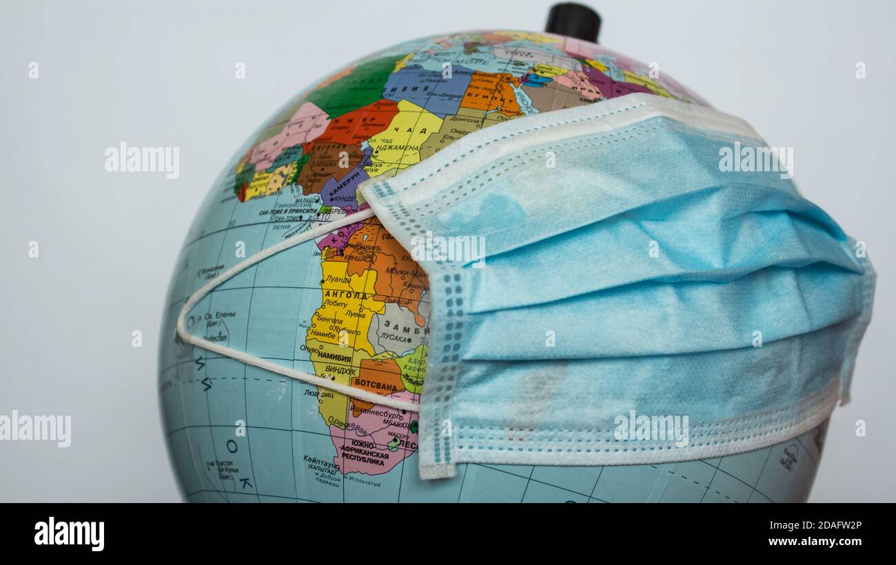 Il globo terrestre indossa una maschera medica. Una maschera medica è indossata su un globo terrestre. Quarantena mondiale, pandemia di coronavirus. Foto Stock