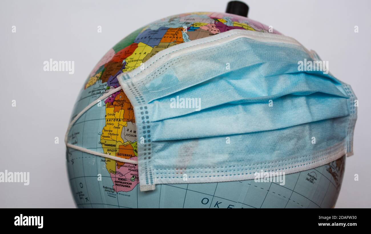Il globo terrestre indossa una maschera medica. Una maschera medica è indossata su un globo terrestre. Quarantena mondiale, pandemia di coronavirus. Foto Stock