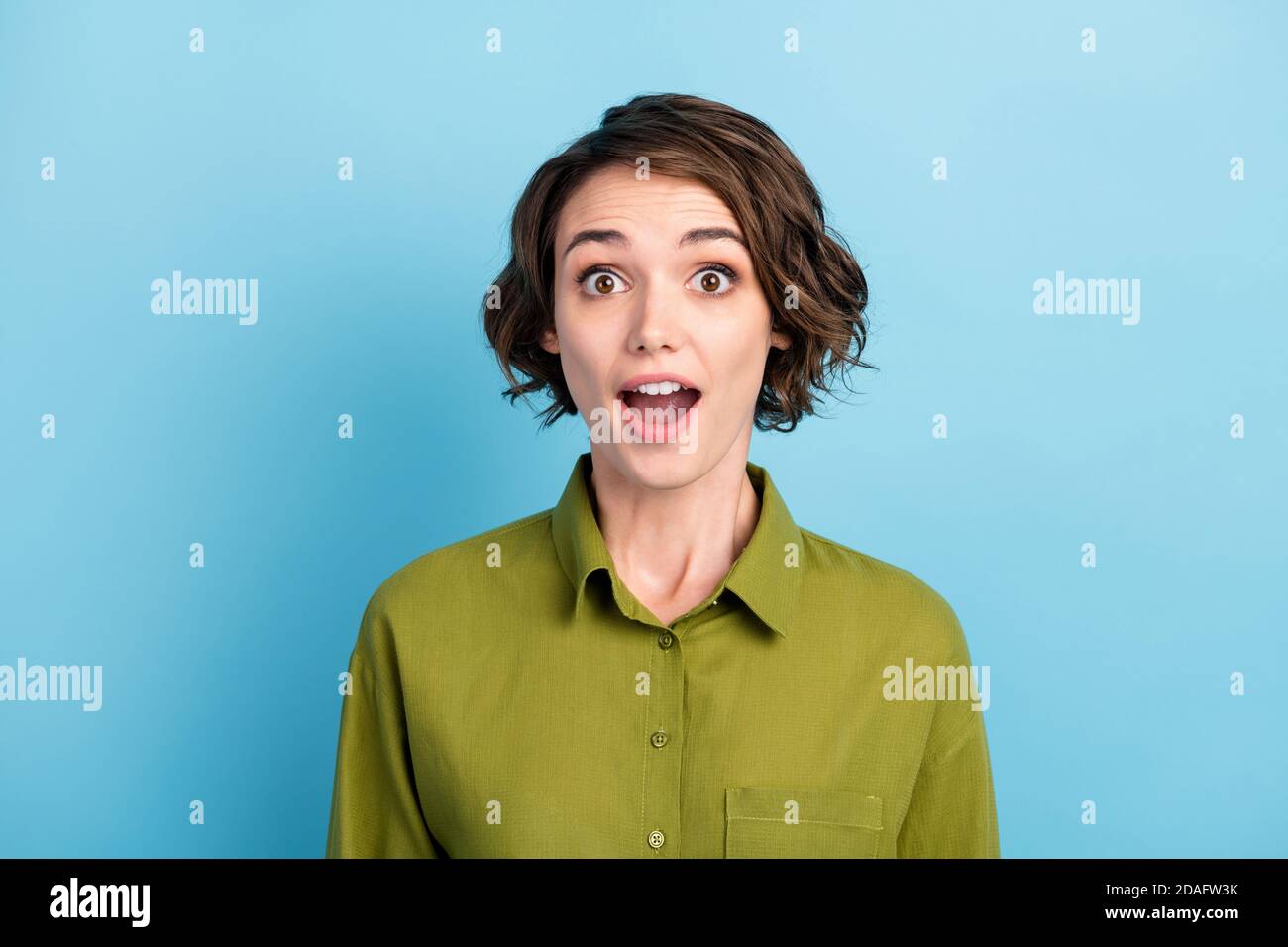 Ritratto fotografico di una giovane donna sorpresa e scioccata che indossa abiti starring con bocca aperta isolata su sfondo blu Foto Stock