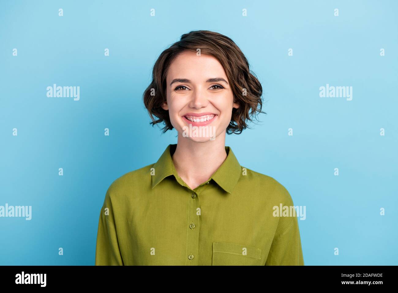 Ritratto fotografico di divertente positivo ottimista ragazza con taglio corto e capelli ondulati sorridenti isolati su sfondo blu Foto Stock