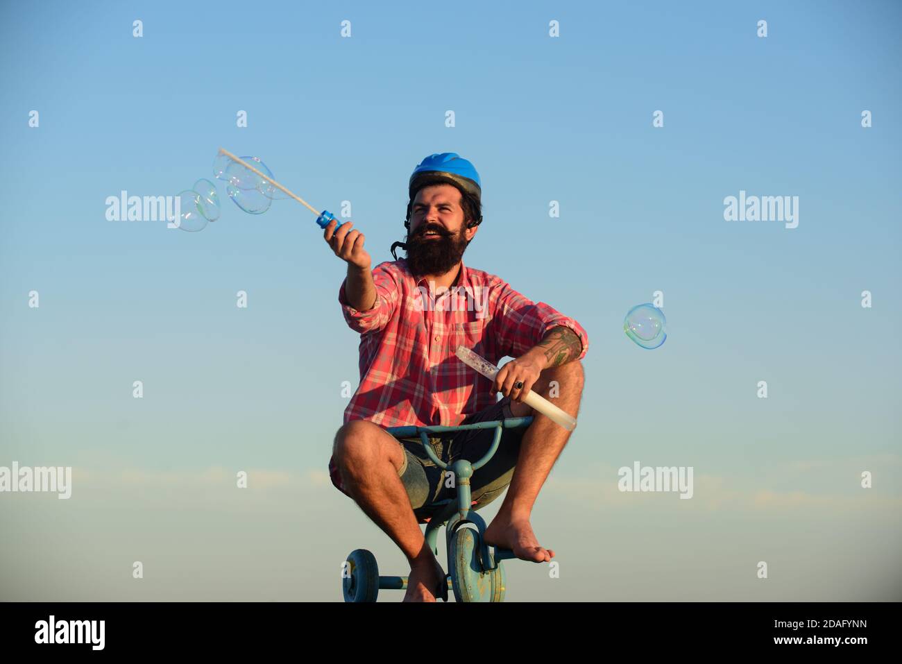 Memoria infantile. Uomo divertente su una bicicletta per bambini. Nercy ciclista cavalcando. Foto Stock
