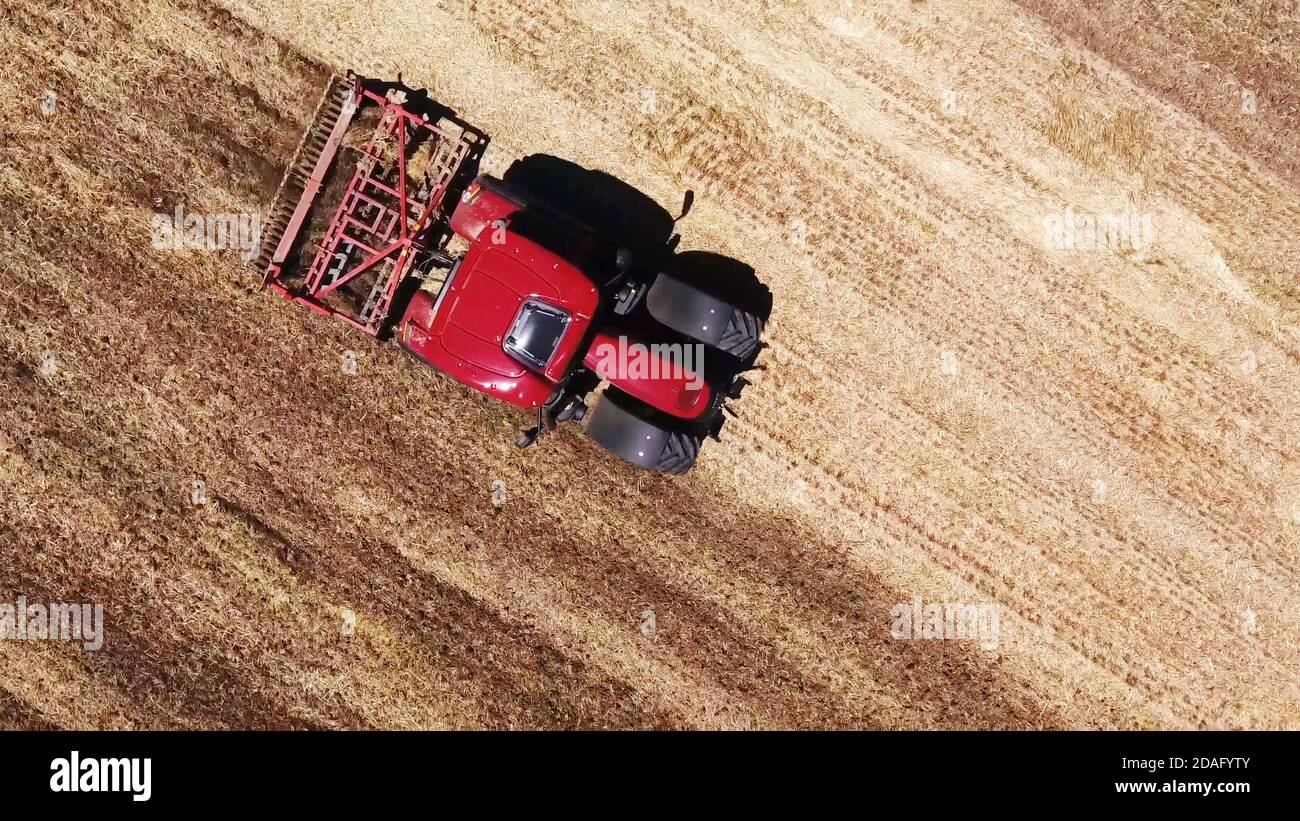 vista dall'alto del trattore agricolo rosso che arava il campo, aratro Foto Stock