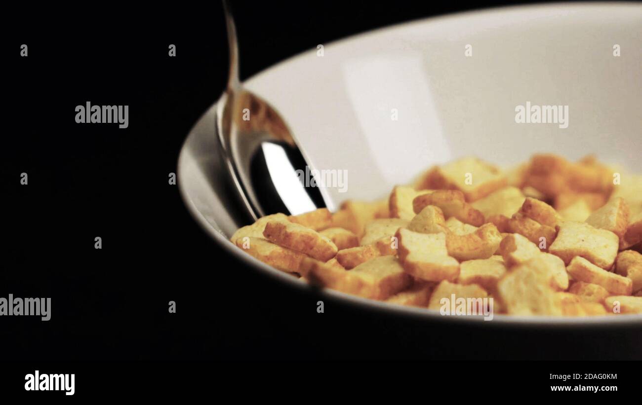 Primo piano di cornflakes colazione in ciotola con cucchiaio in nero copia spazio sfondo. Foto Stock