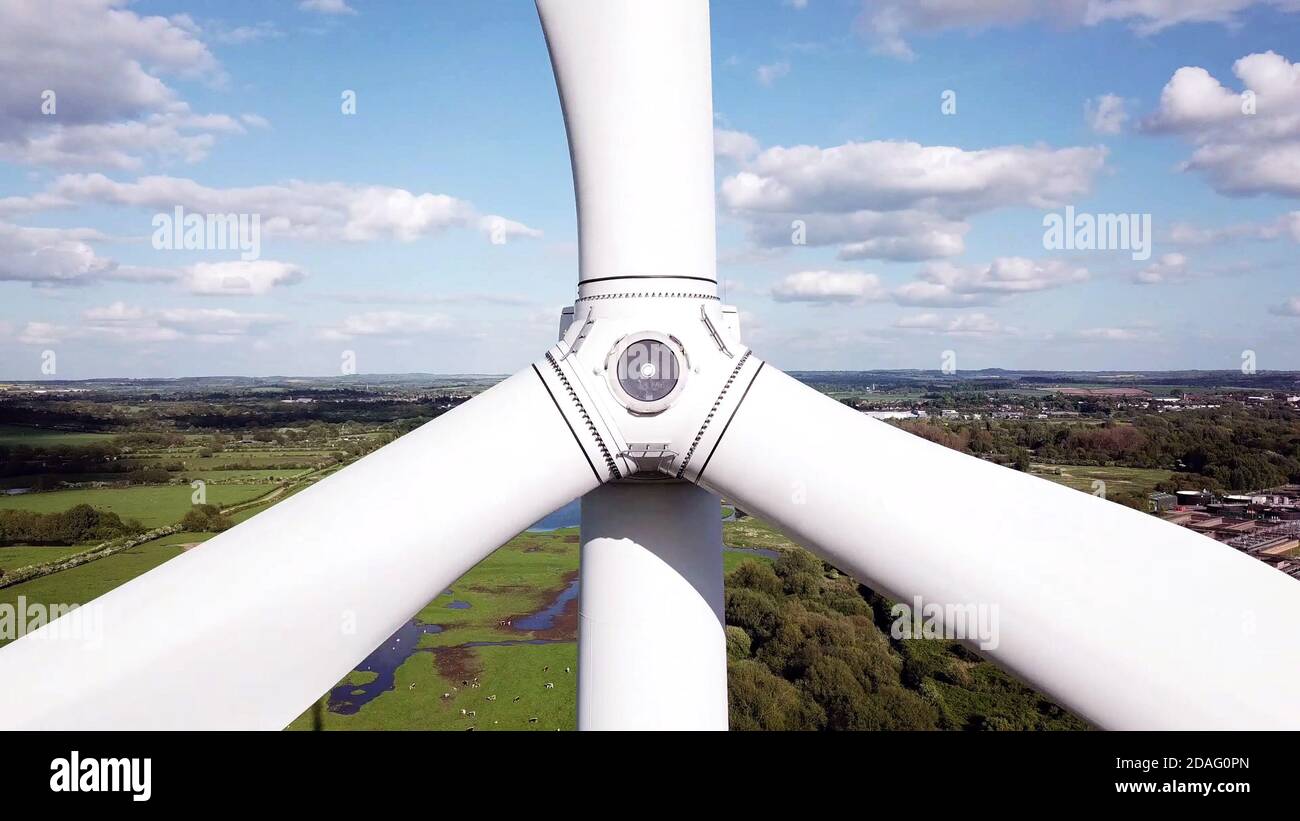le pale delle turbine eoliche si avvicinano dalla vista aerea con l'agricoltura e le aree industriali in background. Foto Stock