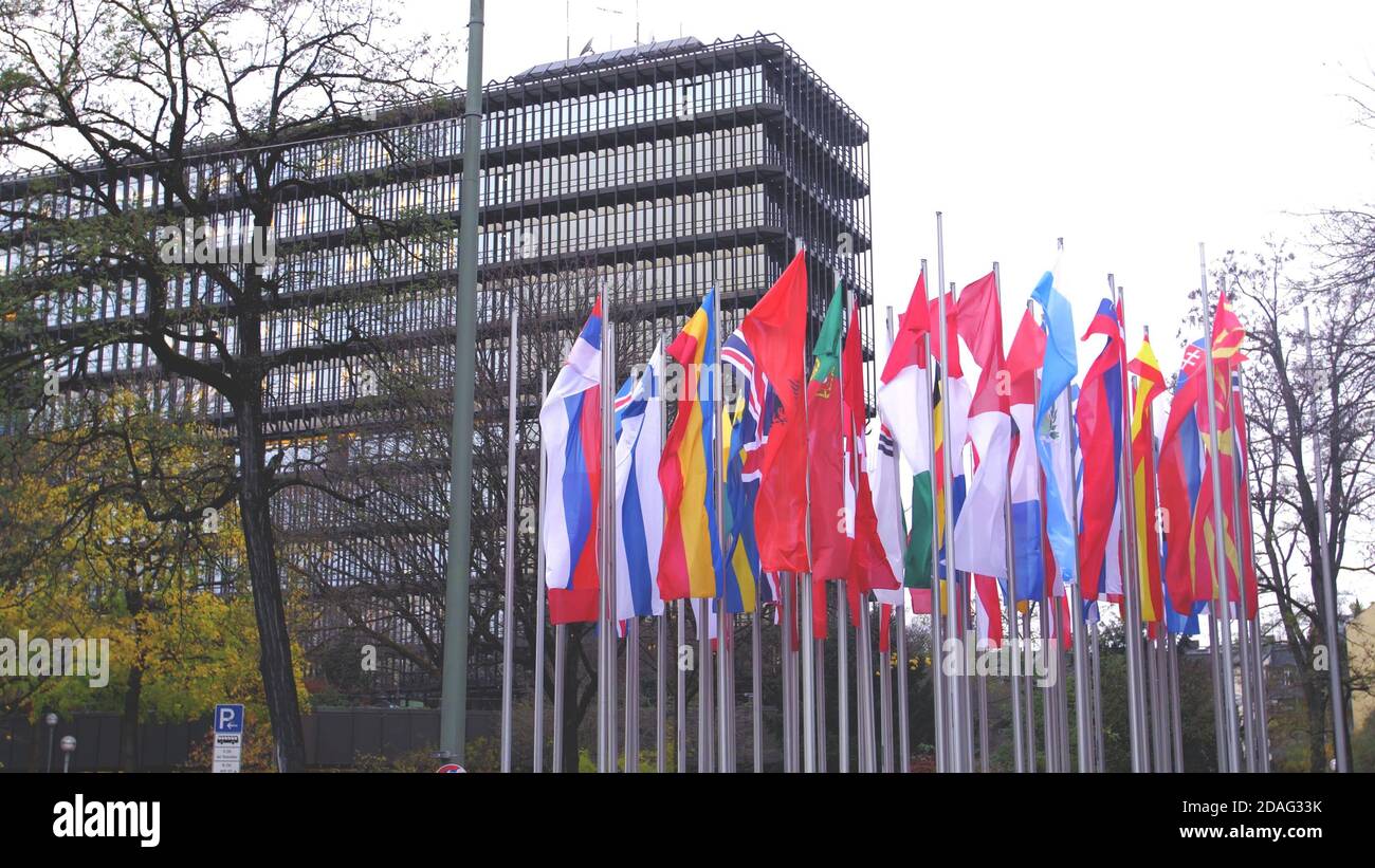 Sventolando bandiere verticali europee accanto a un moderno edificio governativo. Foto Stock