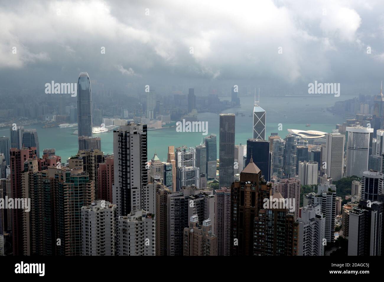 Alti edifici moderni in nebbia e dense nuvole di pioggia Porto di Hong Kong dal punto di vista e acqua verde Foto Stock