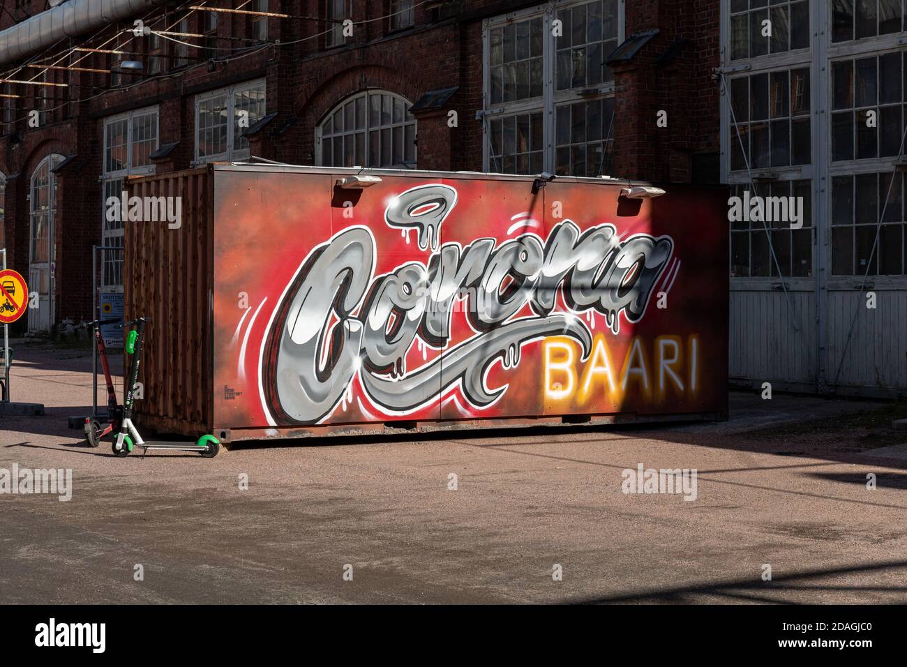 Container marittimo di fronte al Corona Bar presso le vecchie opere di ingegneria ferroviaria del distretto di Konepaja a Helsinki, Finlandia Foto Stock