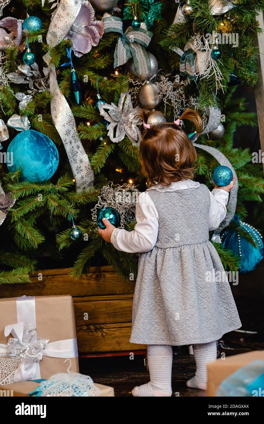 Bambina che decora l'albero di Natale a casa. I bambini decorano il soggiorno per Natale. Stagione invernale. Foto Stock