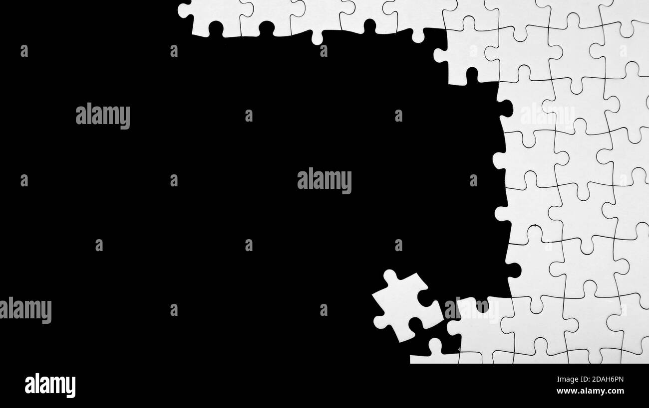 Pezzi di puzzle bianco incompiuto su sfondo nero Foto Stock