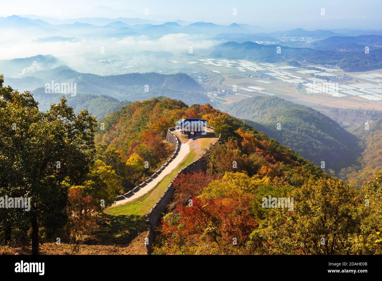Splendido paesaggio autunnale coreano. Foglie d'autunno colorate viste dalla cima della montagna e edifici tradizionali lungo la strada del castello. Foto Stock