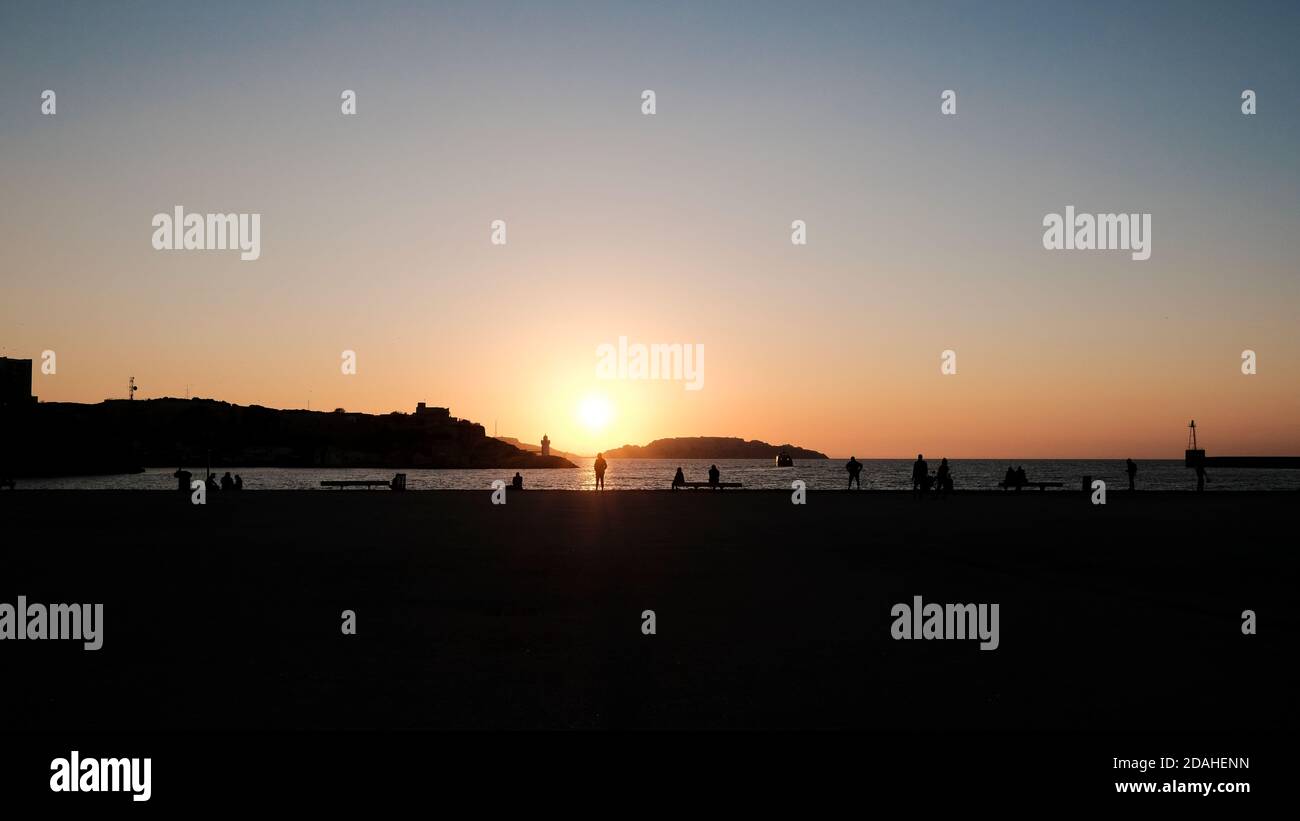 Vista delle banchine al tramonto vicino al Mucem a Marsiglia. Le sagome degli escursionisti si distinguono contro il tramonto durante il periodo pandemico Foto Stock