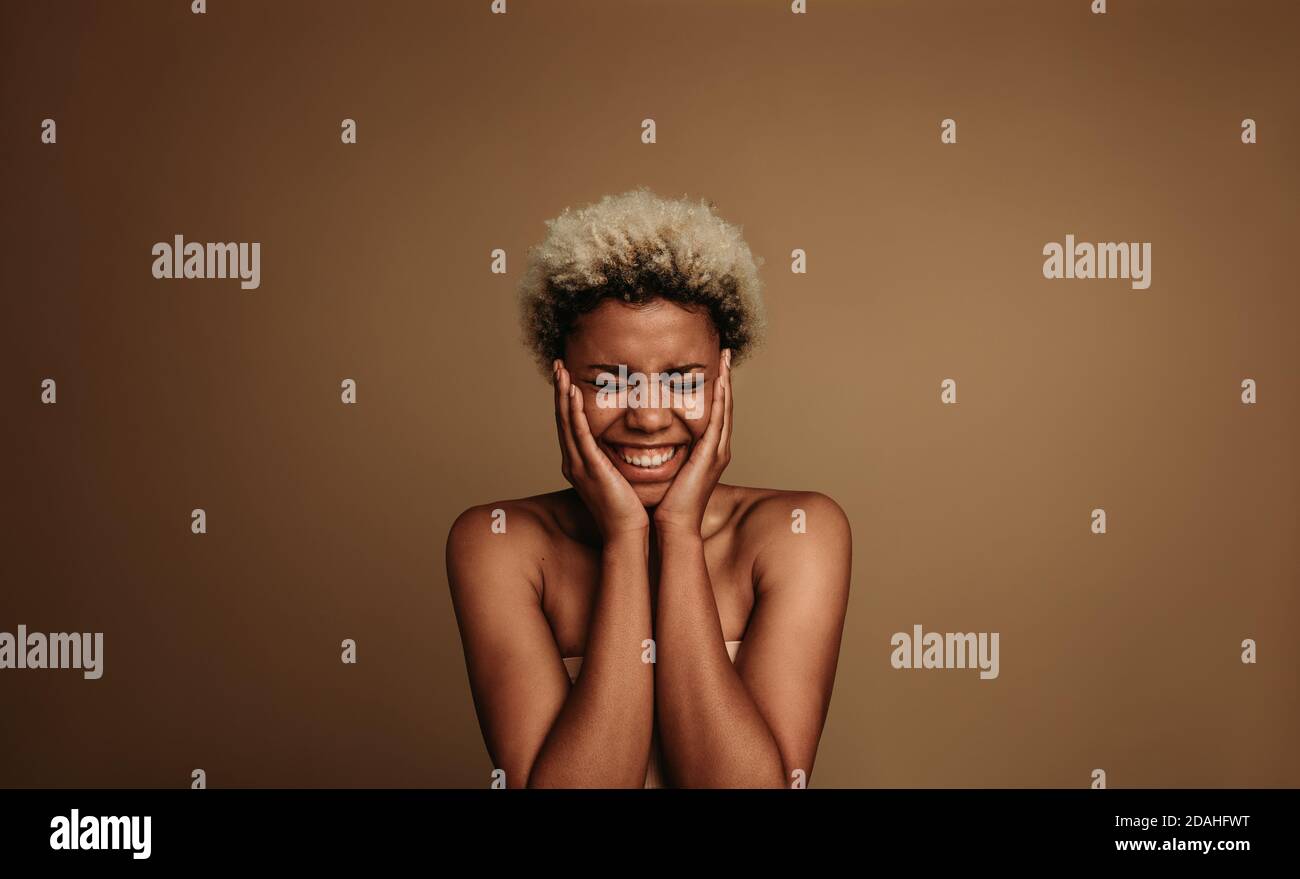 Ritratto di una donna afro-americana eccitata. Donna felice con le mani alle sue guance in un umore eccitato. Foto Stock