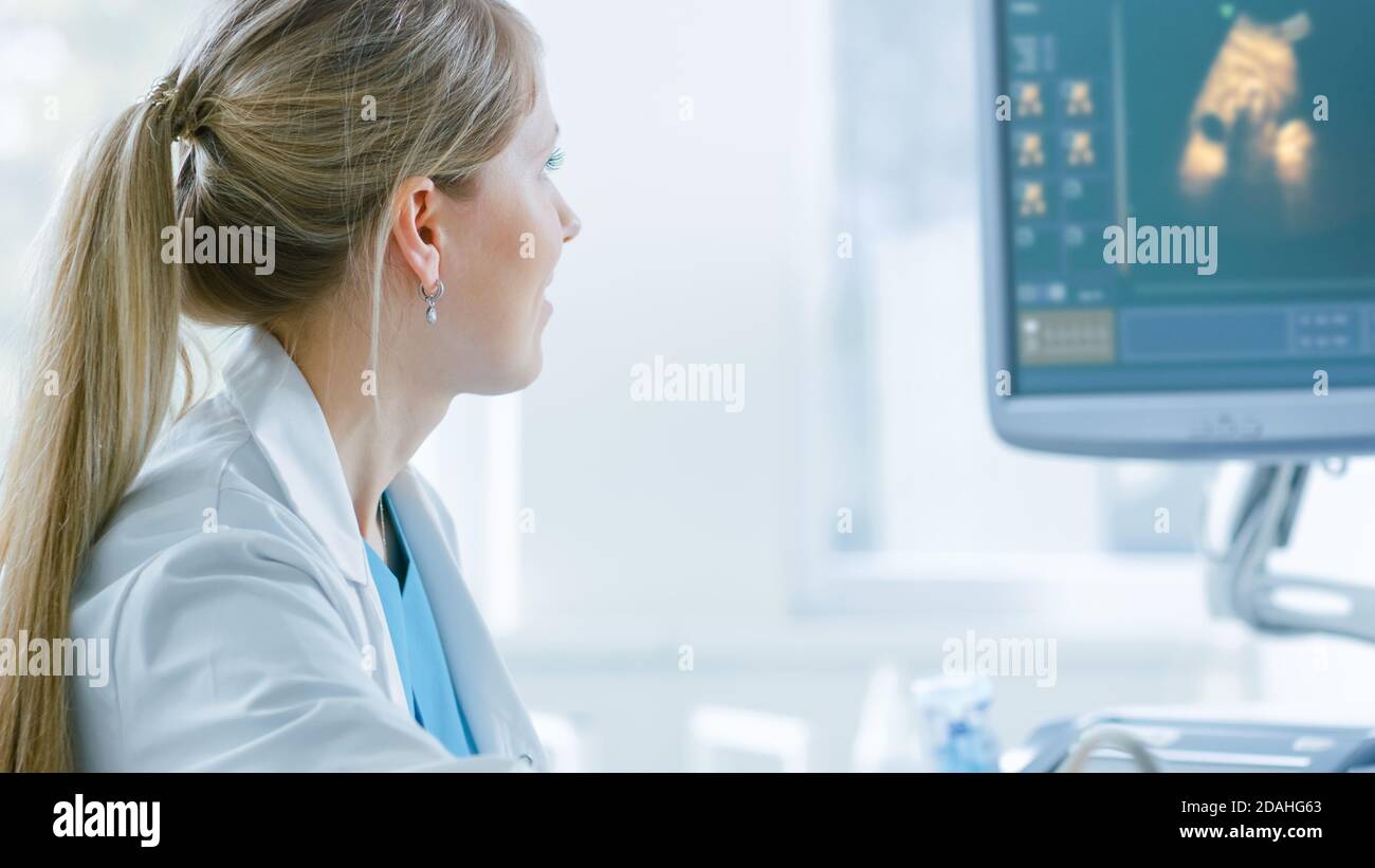 Nell'ospedale, la funzione Close-up Shot di un ostetrico utilizza il trasduttore per la scansione a ultrasuoni ventina della donna incinta. Lo schermo del computer mostra l'immagine 3D Foto Stock