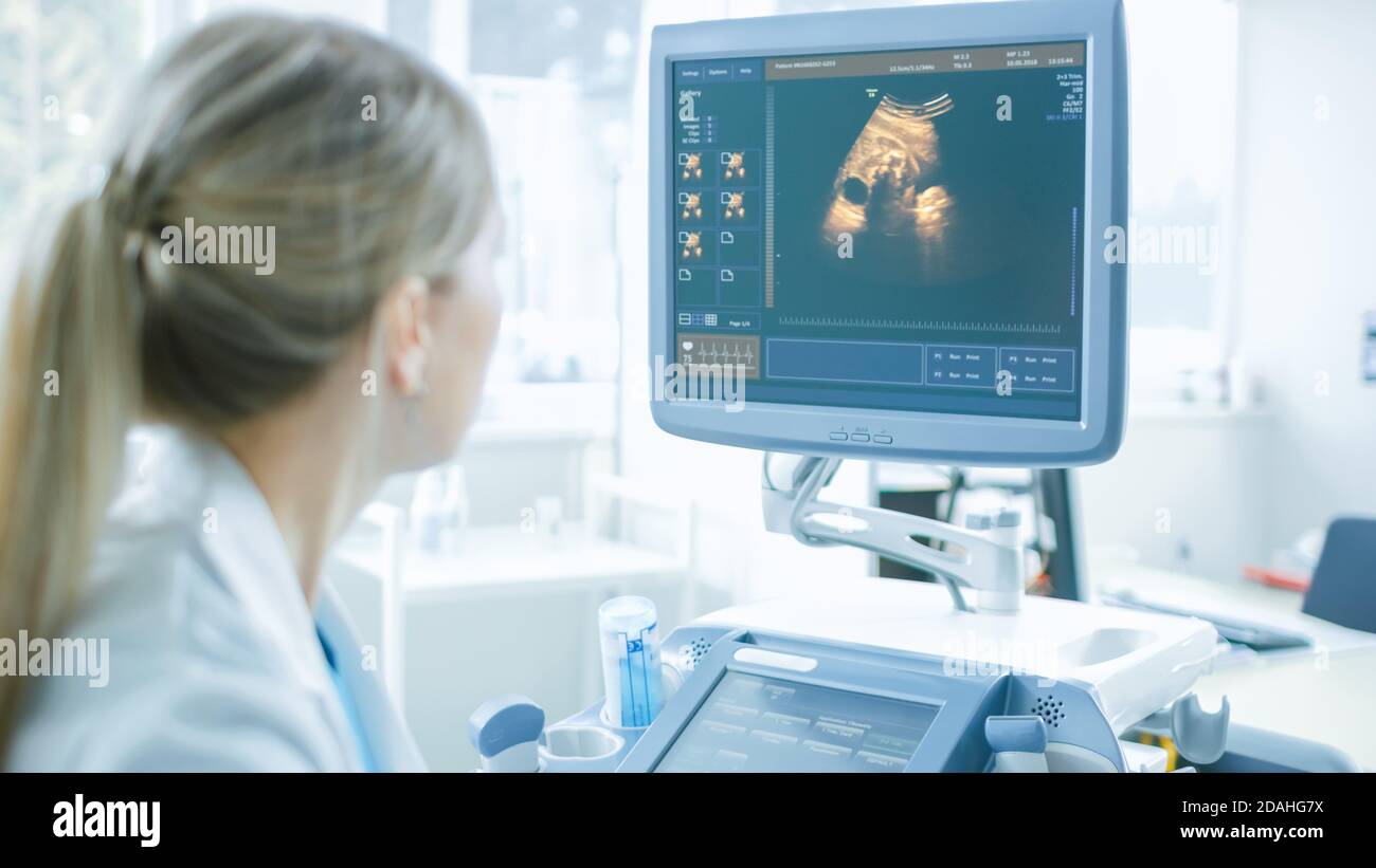 In ospedale, ostetrista che guarda lo schermo del computer del trasduttore per ecografia ecografia scansione di screening Belly della donna incinta Foto Stock