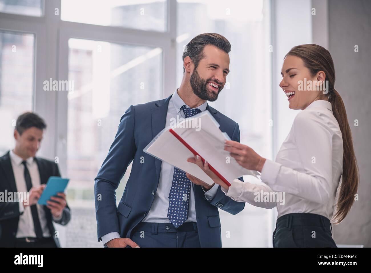 Ridendo uomo e donna con documenti in ufficio Foto Stock