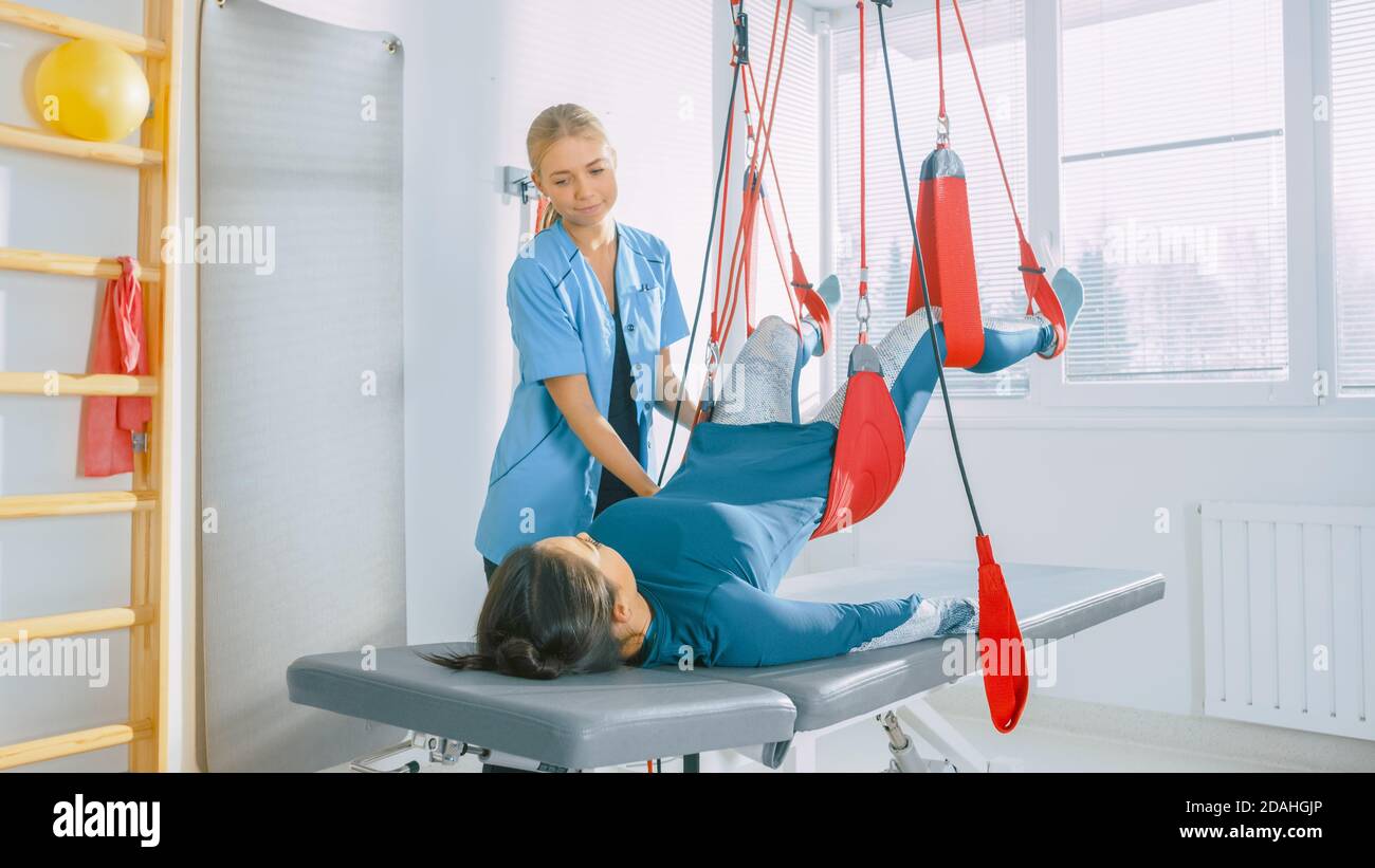 Fisioterapista assiste le donne con trauma, sottoponendo a fisioterapia Riabilitativa su un sistema di corda a sospensione speciale. Alleviare il dolore alla schiena Foto Stock