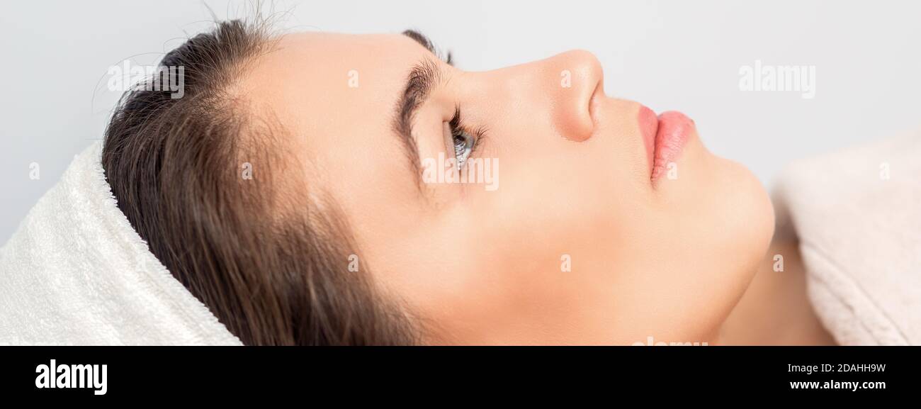 Vista laterale ritratto della giovane donna pessiva che sta sdraiata e in attesa per la procedura cosmetica in salone di bellezza Foto Stock