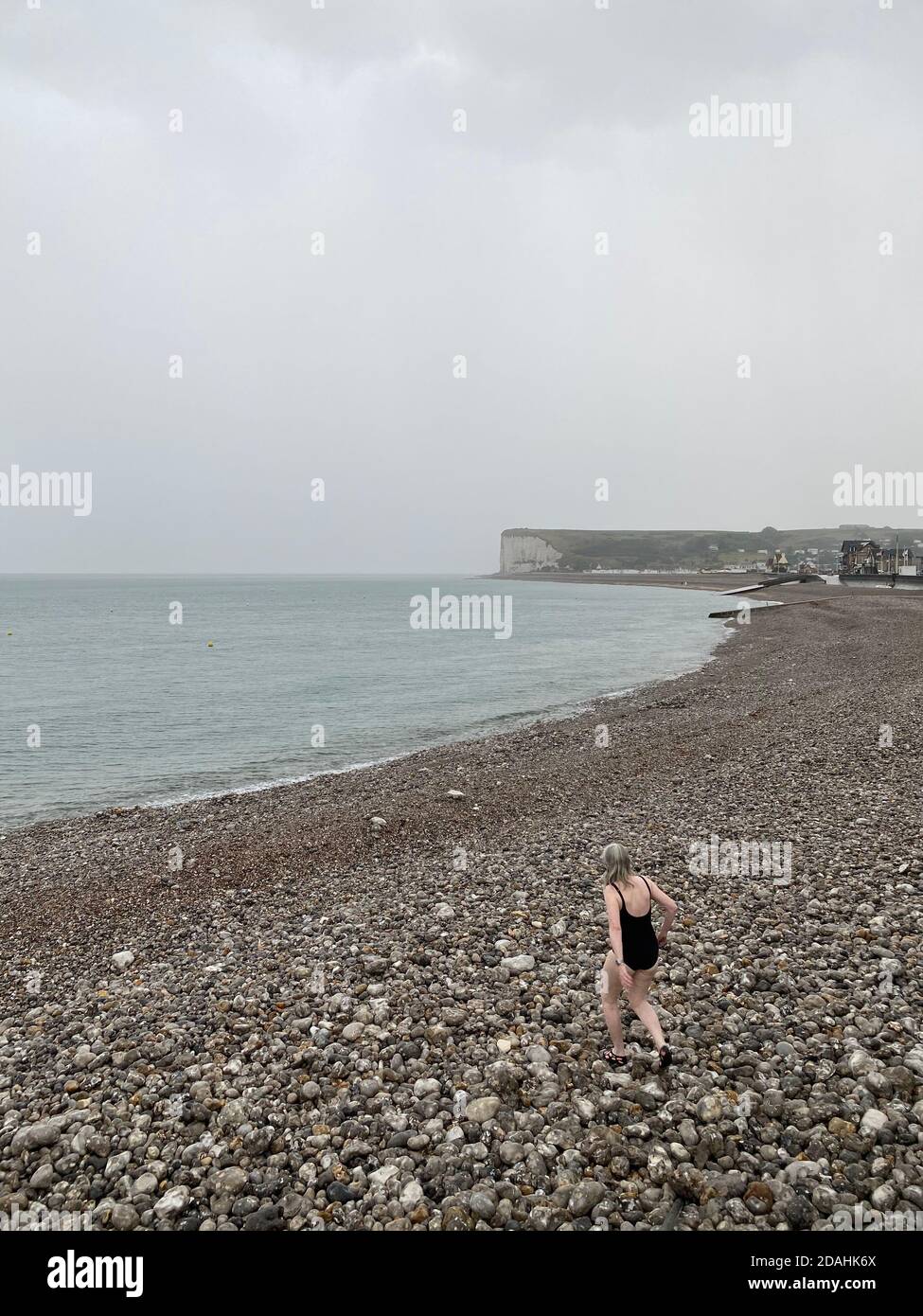 Nuotatrice femminile irriconoscibile che va a nuotare nel mare sotto la pioggia, Costa d'Opale, Normandia, Francia Foto Stock