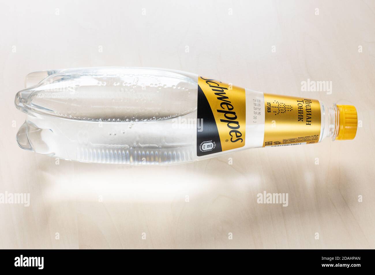 MOSCA, RUSSIA - 4 NOVEMBRE 2020: Vista dall'alto di una bottiglia di acqua tonica indiana di Schweppes sdraiata in edizione russa sulla tavola marrone chiaro. Schweppes è la bacchetta Foto Stock
