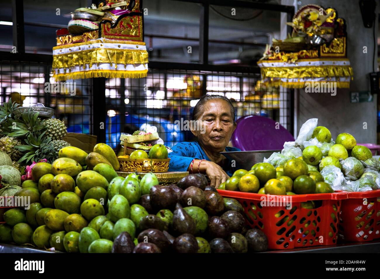 Denpasar, Bali, Indonesia - 8 AGOSTO 2019 : Ritratto di una donna che vende frutta esotica al mercato locale coperto. Foto Stock