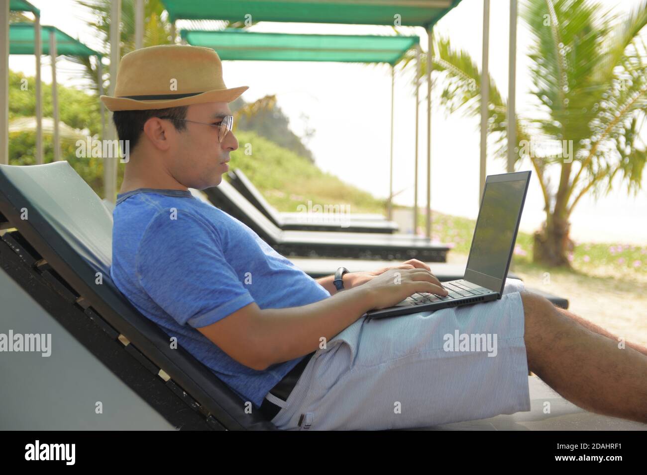 Un uomo che usa il suo laptop e lavora dalla spiaggia di mare, durante questa pandemia dove il lavoro da casa è parte della vita , ora le persone possono lavorare da qualsiasi luogo e da un Foto Stock