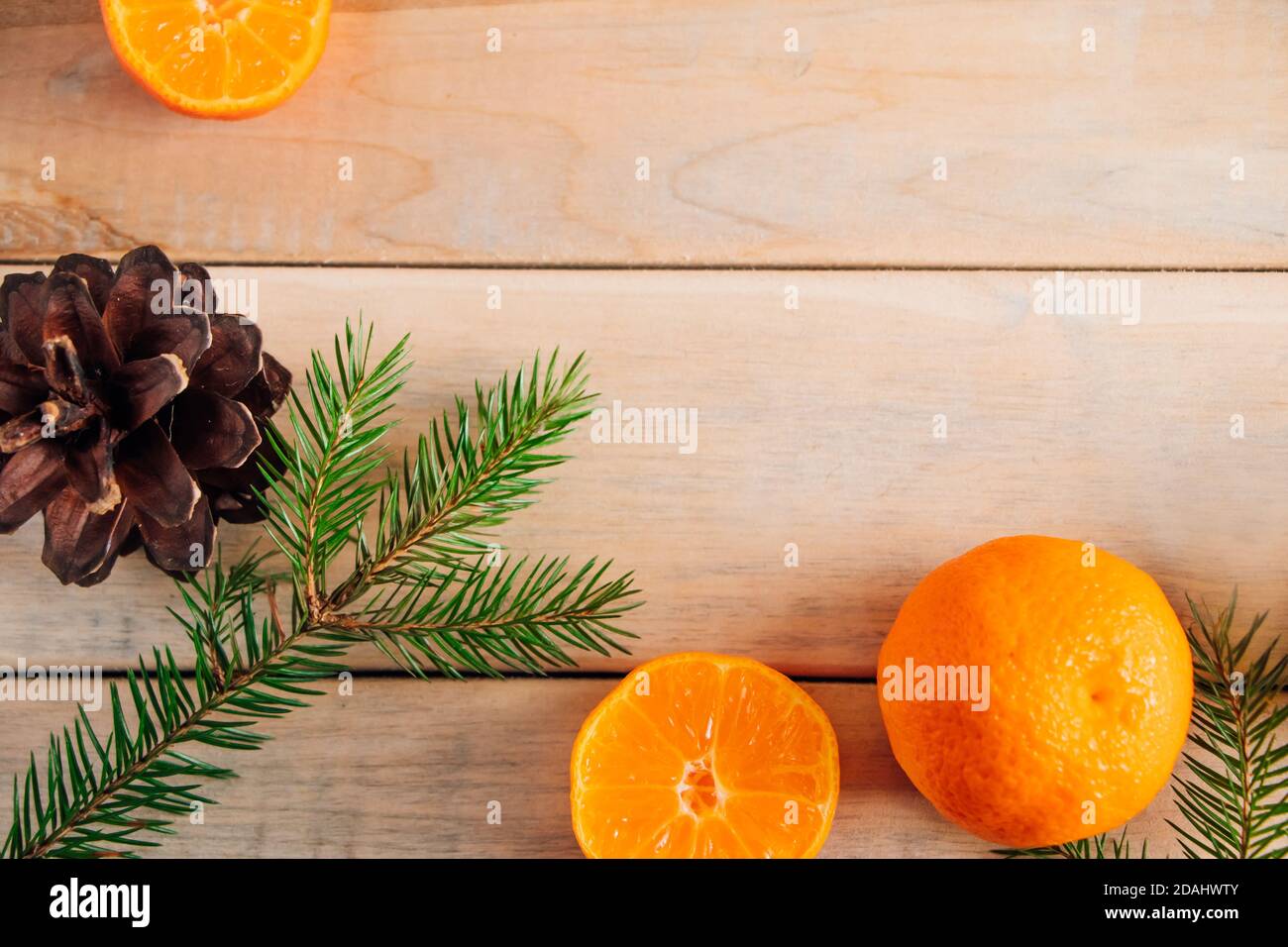 Decorazioni natalizie. Rami di abete, coni e tangerini su sfondo ligneo. Foto Stock