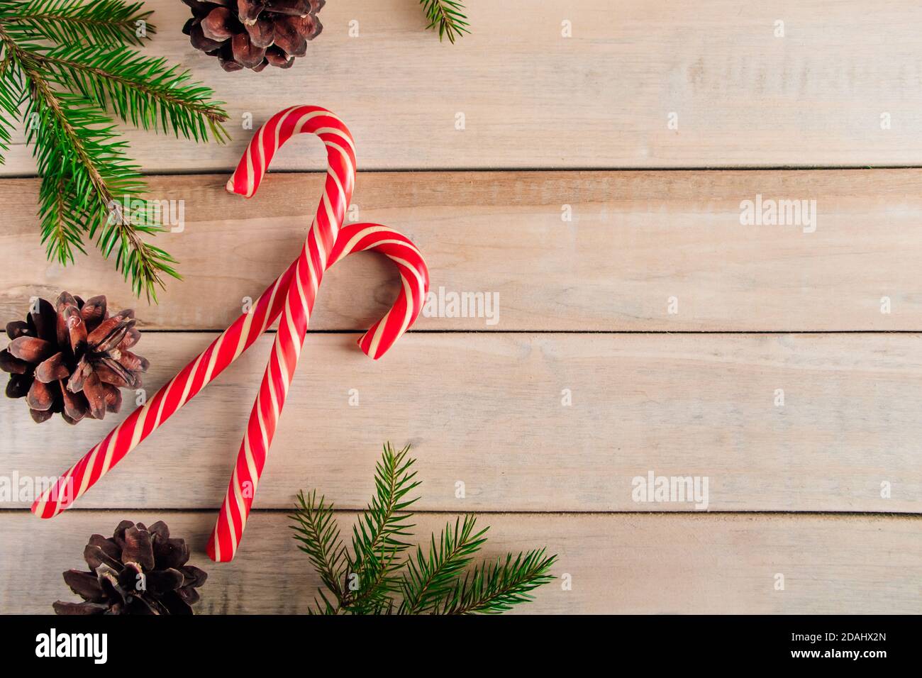 Rami di abete e caramelle su sfondo di legno. Natale e concetto di nuovo anno. Posiziona per il testo. Foto Stock