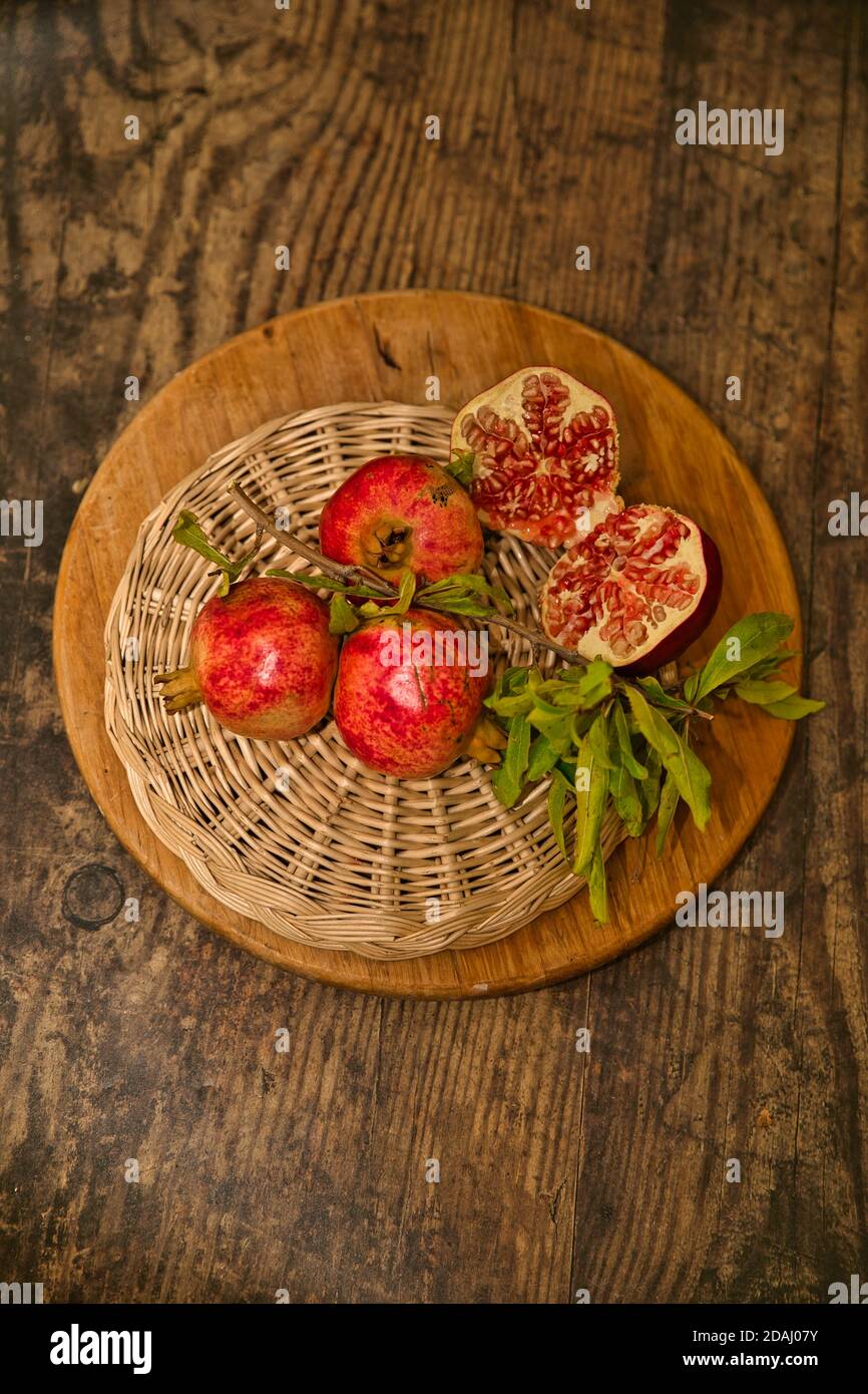 Melograni su un vassoio di paglia con un taglio a metà. Immagine stock. Foto Stock