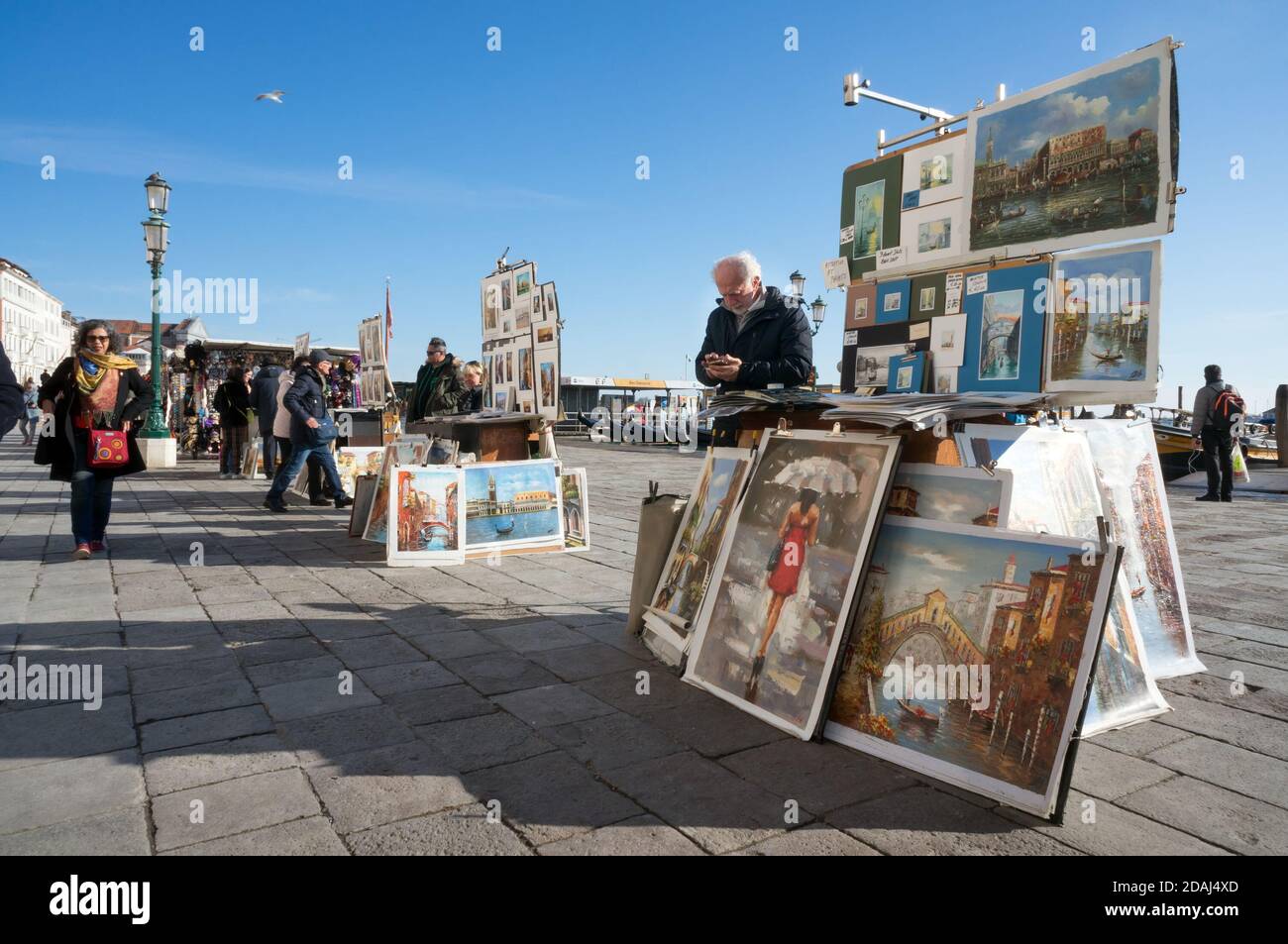 Gli artisti vendono i loro dipinti ai turisti sul lungomare centrale della Riva degli Schiavoni (Slavyanskaya) in una giornata di sole a Venezia. Foto Stock