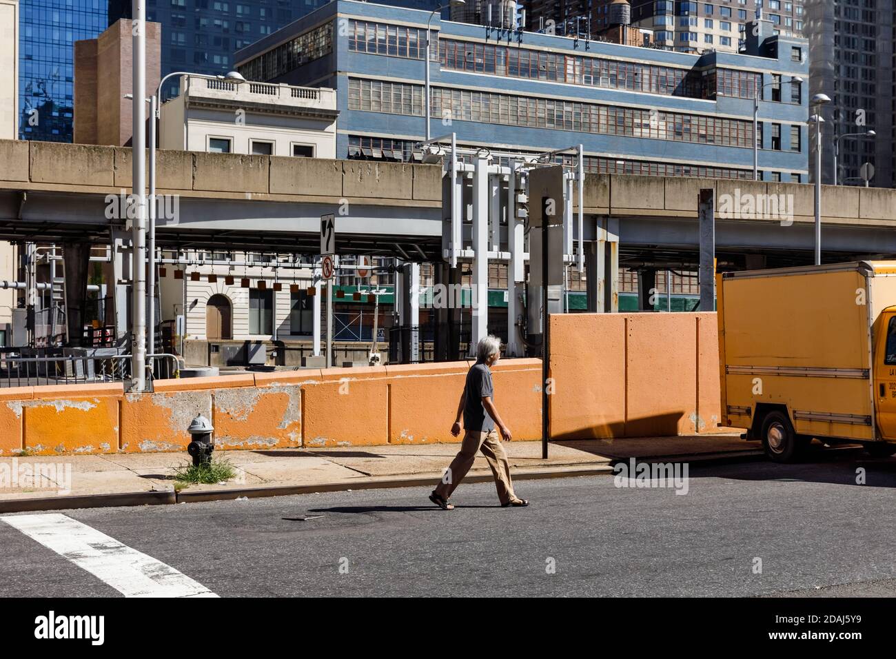 New York, Stati Uniti d'America - 23 settembre 2017: Scena di Manhattan Street. L'uomo OLS cammina lungo una recinzione gialla in cemento per le strade di Manhattan a New York City Foto Stock