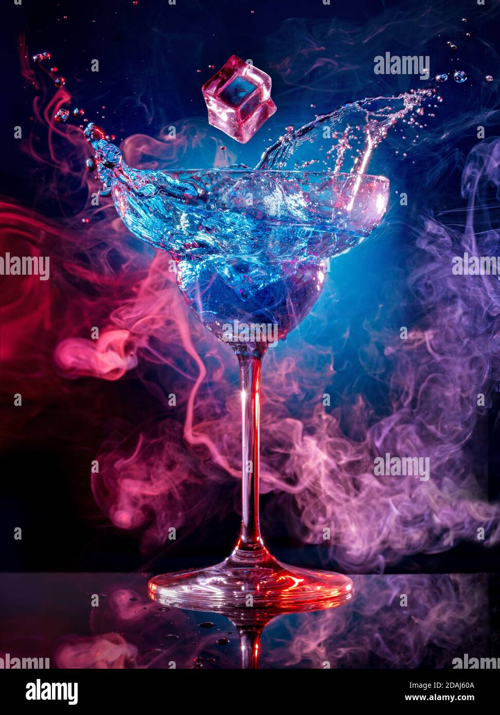 cubo di ghiaccio che cade in un cocktail spruzzi su sfondo fumoso Foto Stock
