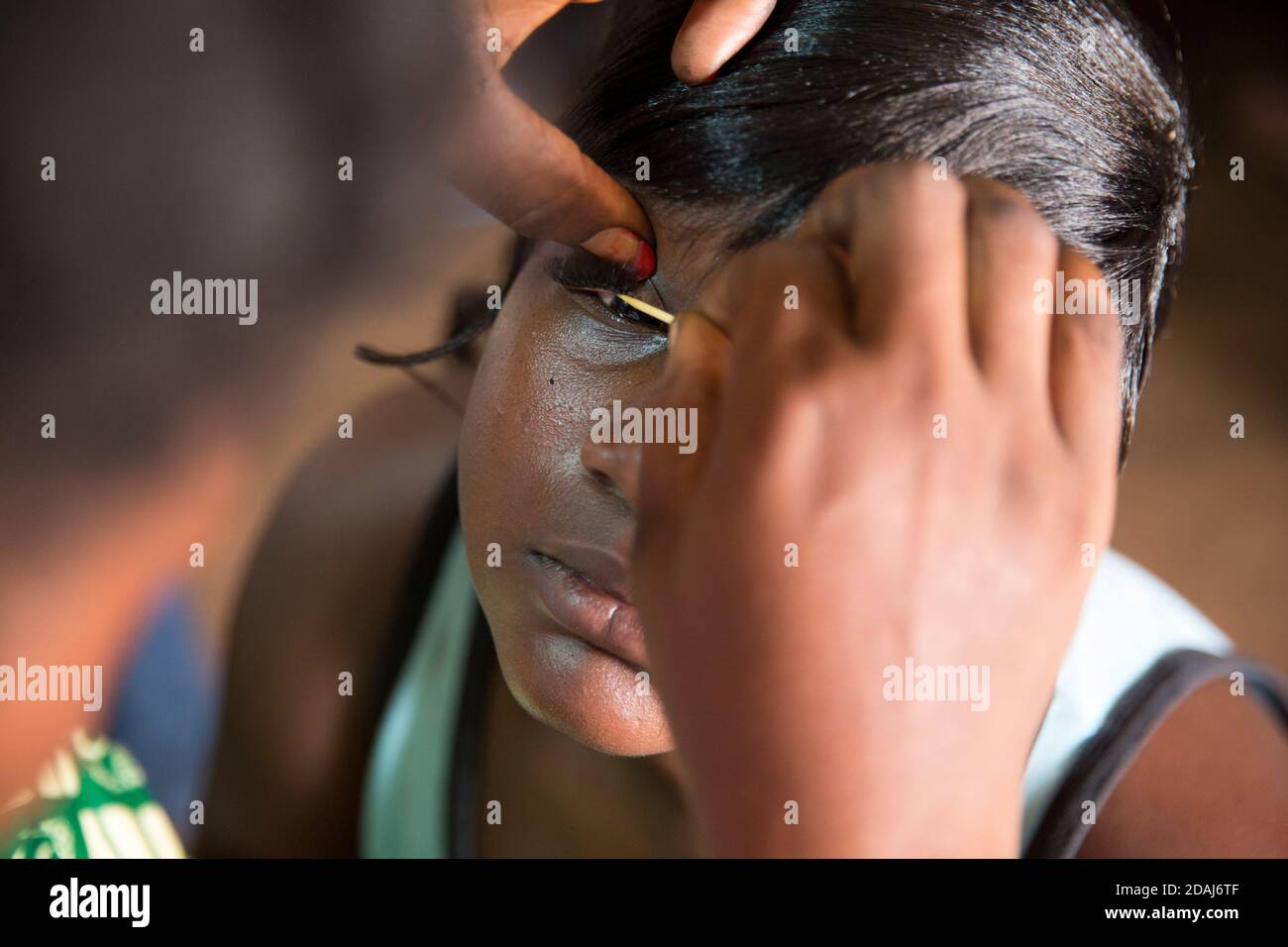 Selingue, Mali, 25 aprile 2015; Oumou Diarra, 32 anni, sta facendo i capelli delle donne 20 e qui sta attaccando le ciglia false. Foto Stock