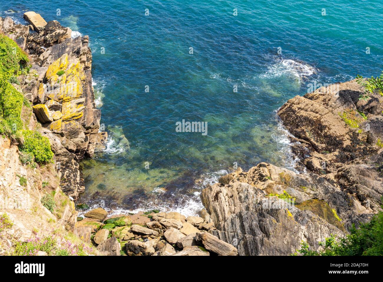 Onde che si infrangono su rocce sulla riva del Fowey estuario, Fowey, Cornovaglia, Regno Unito Foto Stock