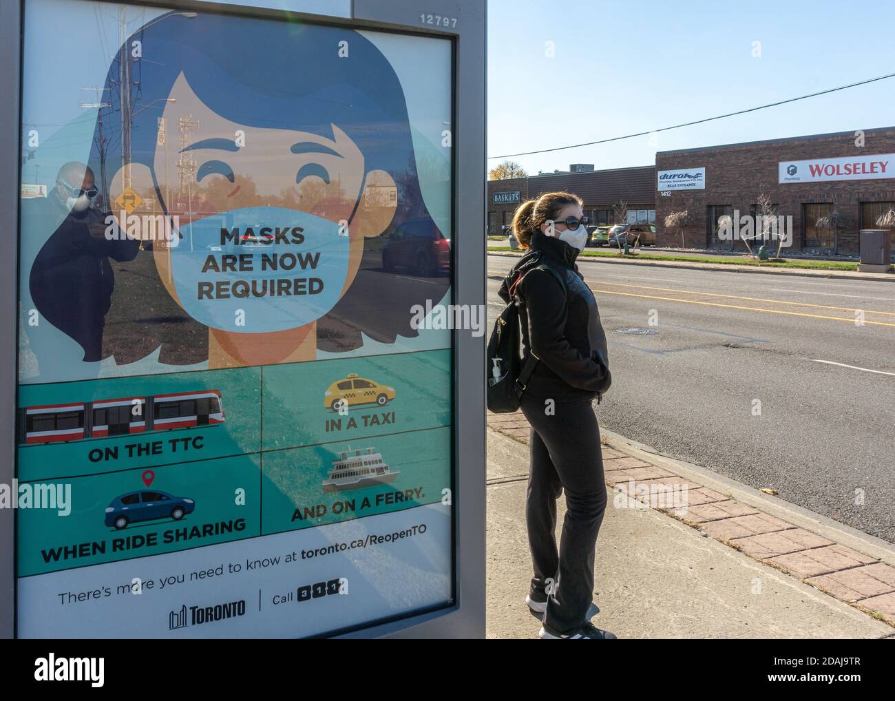 Una donna in attesa di un autobus TTC durante il periodo Coronavirus a Toronto, Canada. Foto Stock