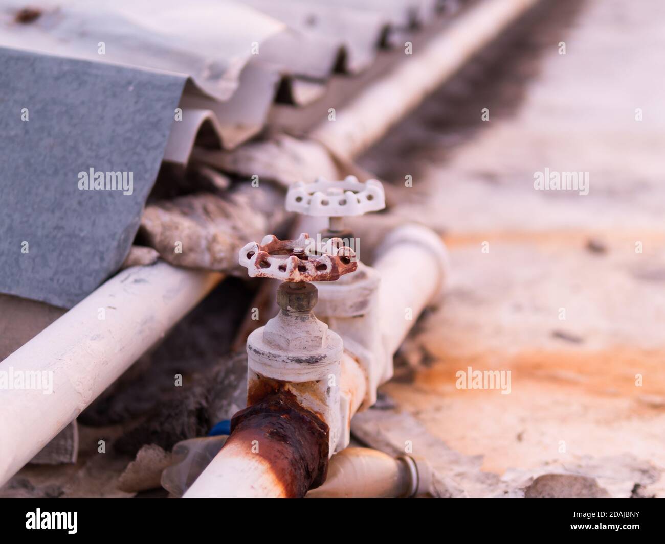 Valvole, tubi e tubi idraulici danneggiati e molta ruggine, causando frequenti perdite d'acqua. Foto Stock