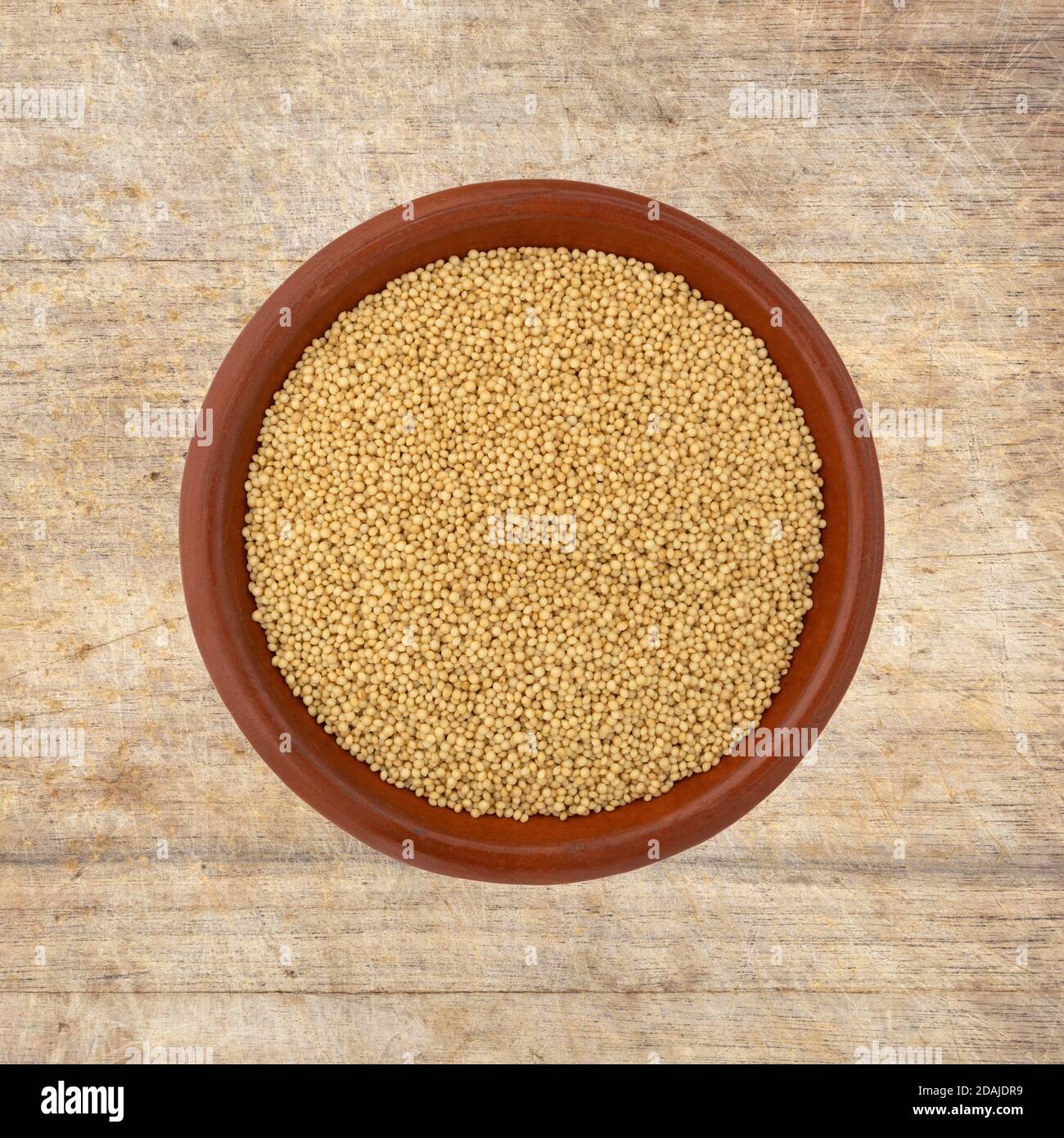 Vista dall'alto dei semi di amaranto in una piccola ciotola sopra un vecchio tagliere. Foto Stock