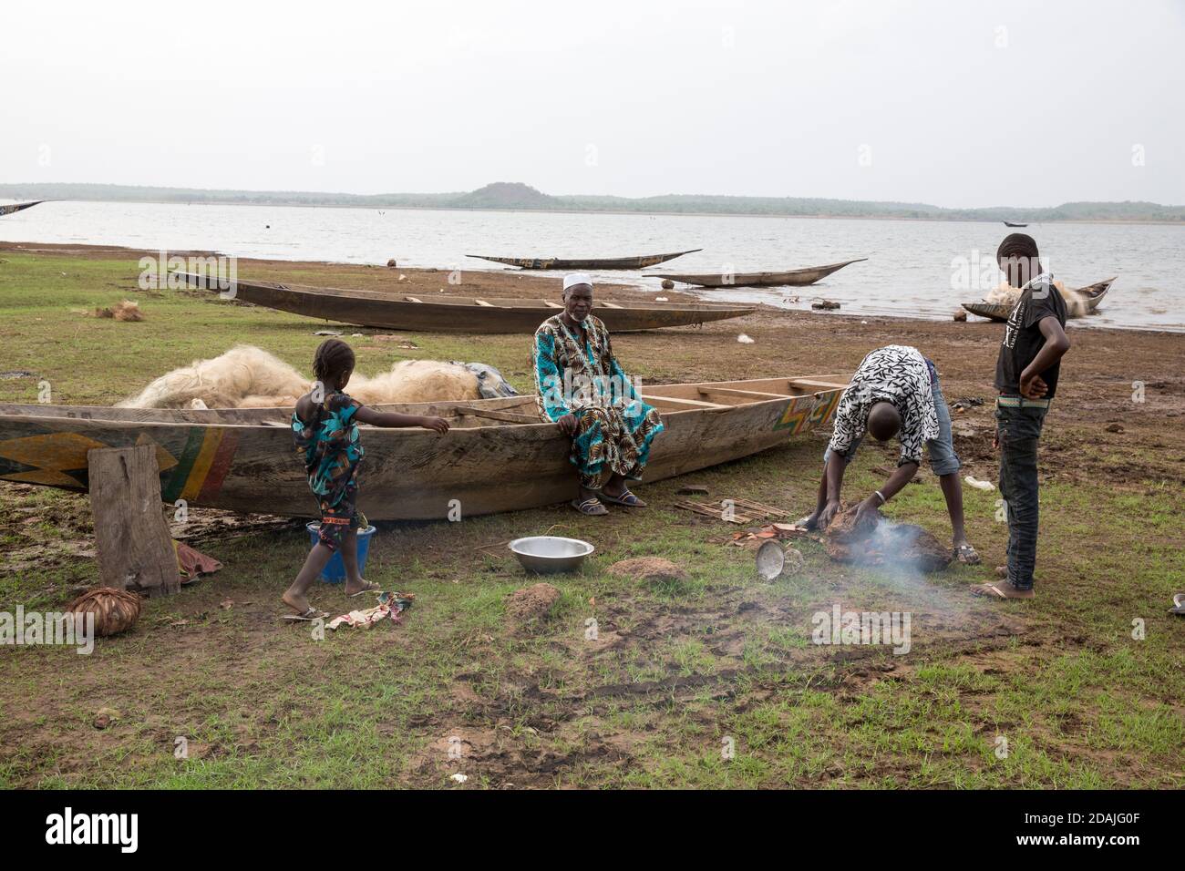 Selingue, Mali, 27 aprile 2015; Boubacar Kente, 70 è un pescatore. Vuole ripristinare la sua vecchia barca sigillandola con grasso naturale estratto dalle noci di alberi caritici nativi (shea). Boubacar dice che prima che la diga fosse costruita il livello dell'acqua era molto più basso, ci erano molti villaggi nel letto del fiume e molti complotti del giardino. Tutti questi sono stati persi quando la diga è stata costruita e la gente si è ricollocata. I pescatori di Bozo da Mopti e Segou arrivano ora ogni stagione secca a causa dell'abbondanza di pesci nel nuovo lago di diga, e alcuni come lui rimangono tutto l'anno. Foto Stock
